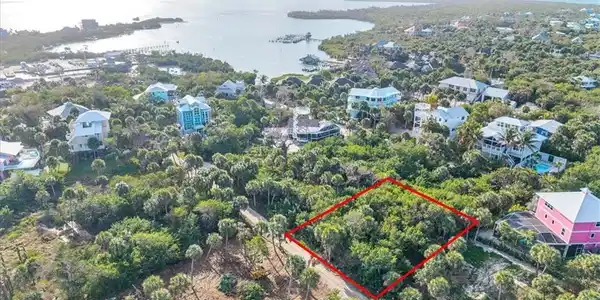 Image 3: Aerial view of lot (outlined in red) with North Captiva's harbor and marina visible &mdash; boat in, step off, and walk home. Island life doesn't get more convenient than this.