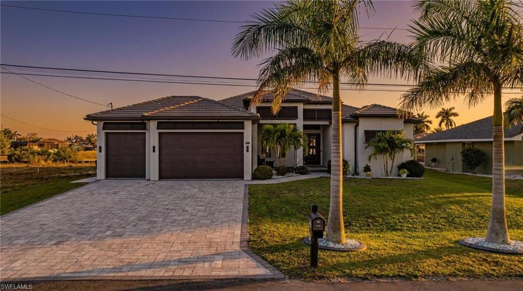 Image 1: Prairie-style house with a lawn, an attached garage, decorative driveway, and a tile roof