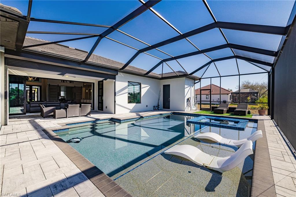 Image 2: Integrated pool / hot tub featuring an outdoor hangout area, a sunroom, a patio, and glass enclosure