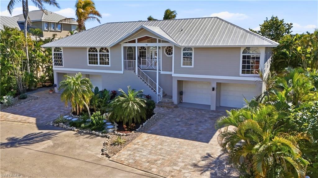 Image 1: Coastal home with a garage, stairway, and decorative driveway - Virtually Edited Image