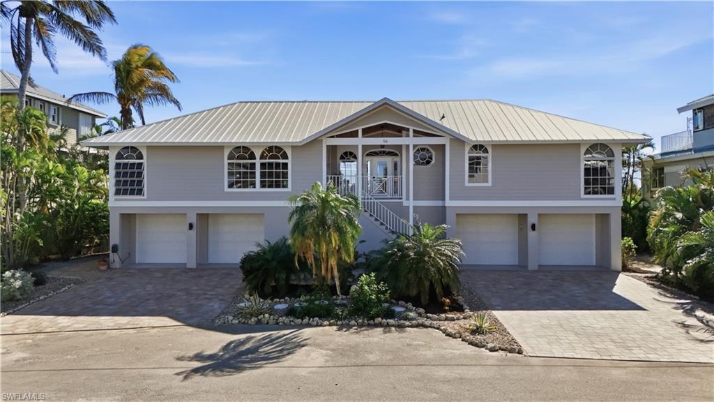 Image 2: Coastal home with a garage, stairway, and decorative driveway - Virtually Edited Image