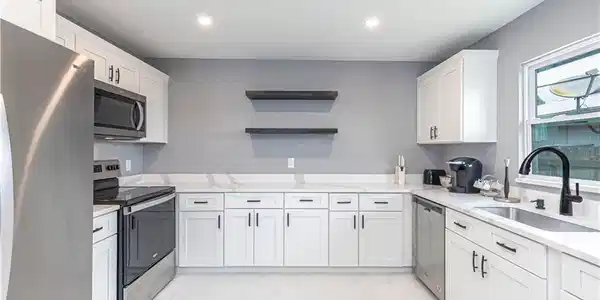 Image 4: Kitchen with stainless steel appliances, white cabinetry, open shelves, light stone counters, and recessed lighting