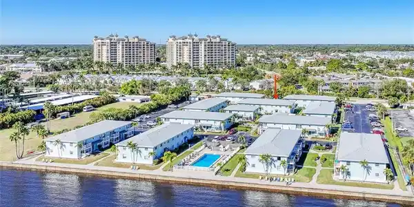 Image 2: Waterfront multi-unit property featuring a communal swimming pool, ample parking, and mature palm trees
