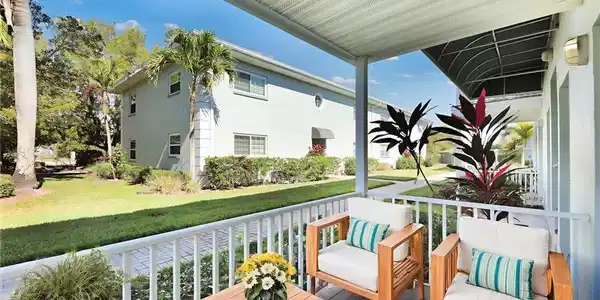 Image 4: virtually staged Covered outdoor patio with wood-finish flooring, white railing, and exterior lighting fixtures