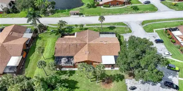Image 2: Property featuring a brown shingle roof, a screened patio, and mature landscaping