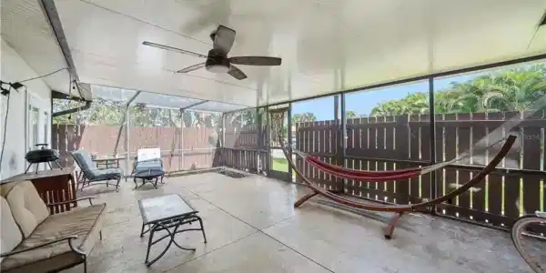 Image 4: Screened patio featuring a ceiling fan, concrete flooring, and a privacy fence