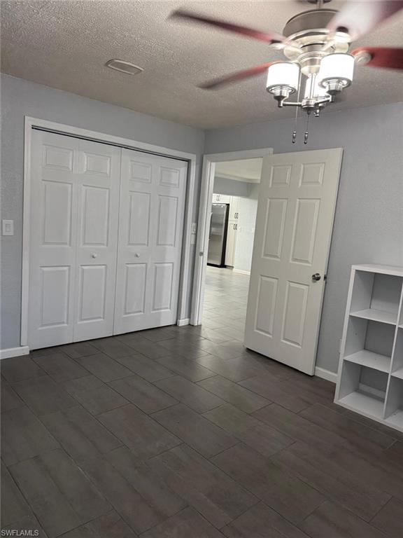 Image 3: Bedroom ceiling fan, a textured ceiling, and dark wood-style flooring