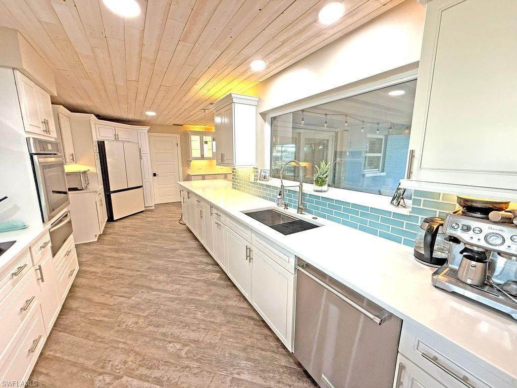 Image 3: Kitchen with stainless steel appliances, decorative backsplash, white cabinetry, light wood finished floors, and recessed lighting
