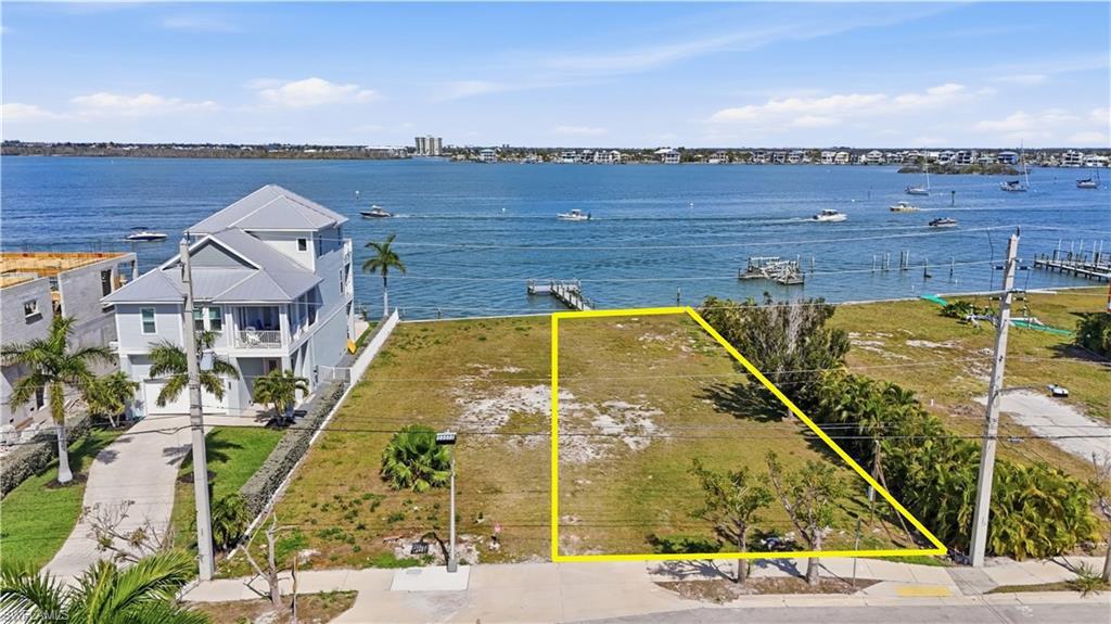 Image 2: Aerial overview of property's location with property parcel outlined and a nearby body of water - Virtually Edited Image
