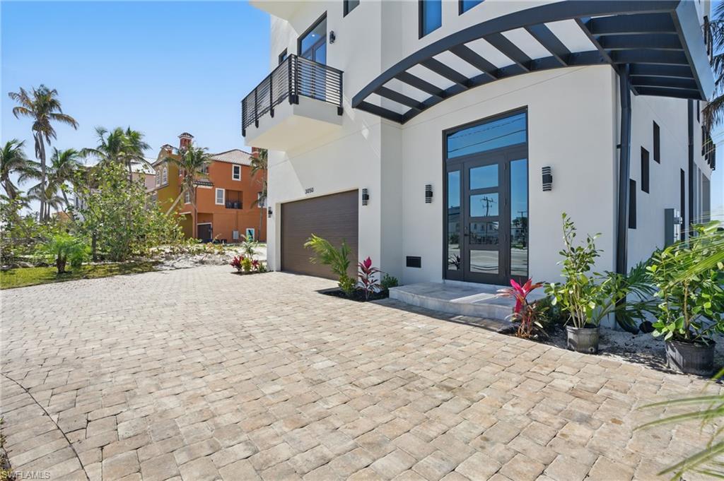 Image 2: Entrance to property featuring stucco siding, french doors, a garage, and decorative drivewayVirtually Enhanced