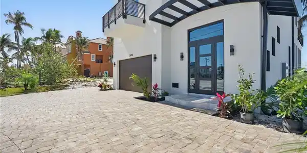 Image 2: Entrance to property featuring stucco siding, french doors, a garage, and decorative drivewayVirtually Enhanced