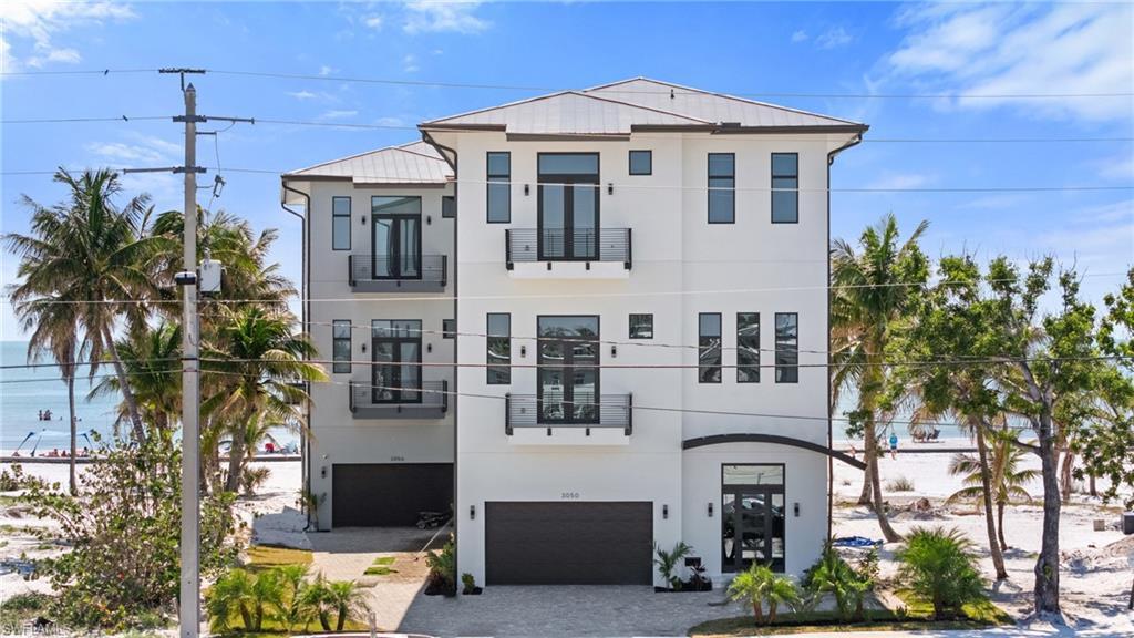 Image 3: Contemporary home with stucco siding, decorative driveway, and a garageVirtually Enhanced