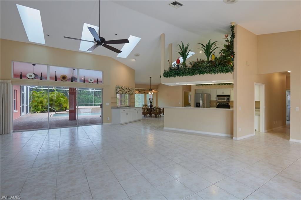 Image 2: Unfurnished living room with high vaulted ceiling, a skylight, light tile patterned floors, and baseboards