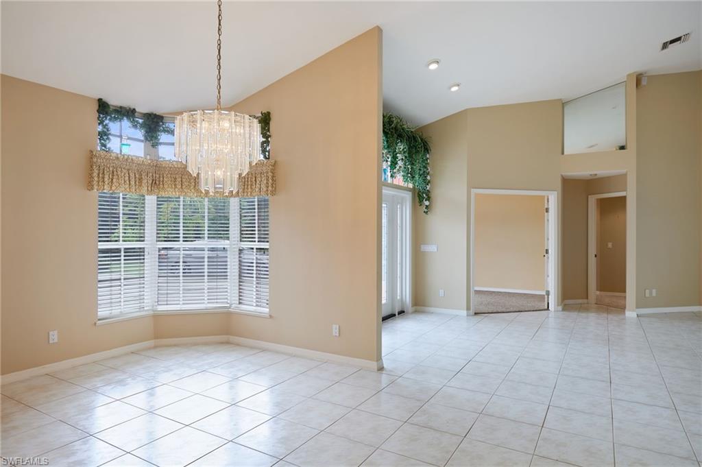 Image 3: Unfurnished dining area featuring high vaulted ceiling, a chandelier, light tile patterned flooring, and baseboards