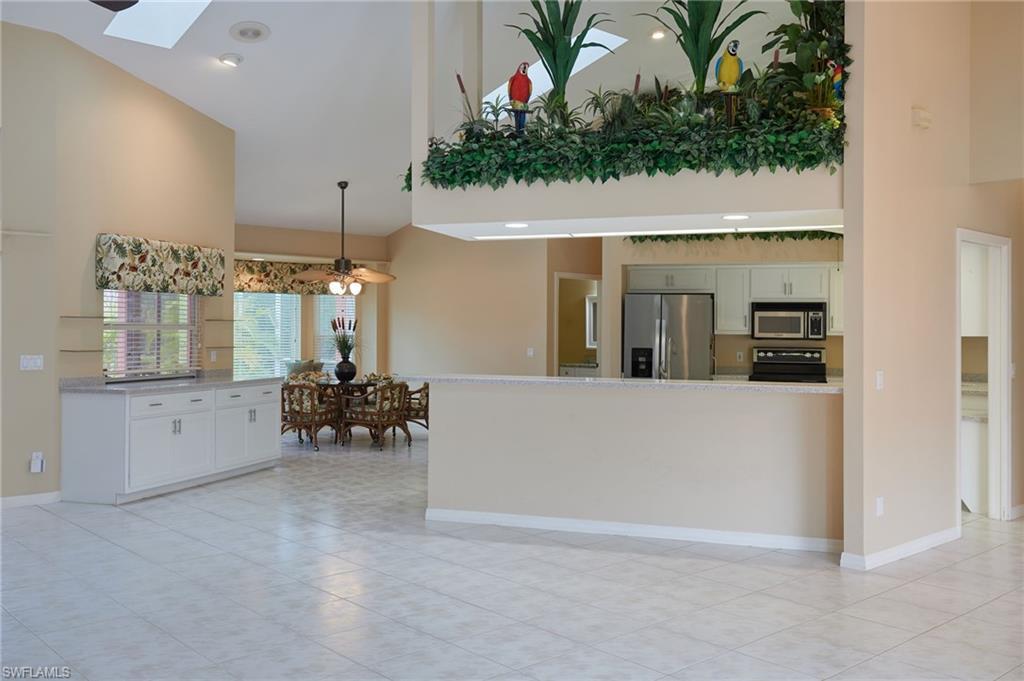 Image 4: Kitchen featuring appliances with stainless steel finishes, high vaulted ceiling, a skylight, light tile patterned flooring, and decorative light fixtures