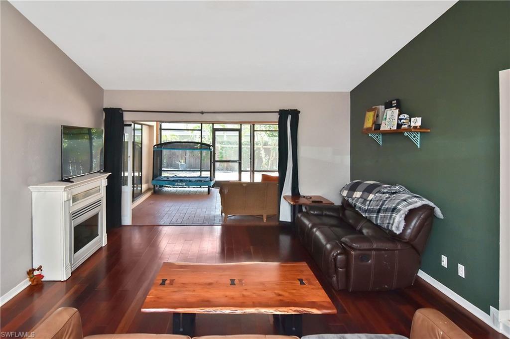 Image 3: Living room featuring dark wood-style floors, vaulted ceiling, and a glass covered fireplace