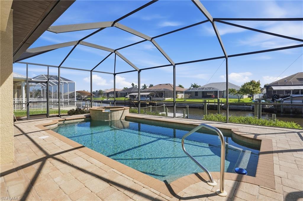 Image 2: Integrated pool / spa featuring a residential view, a sunroom, a patio, a water view, and glass enclosure