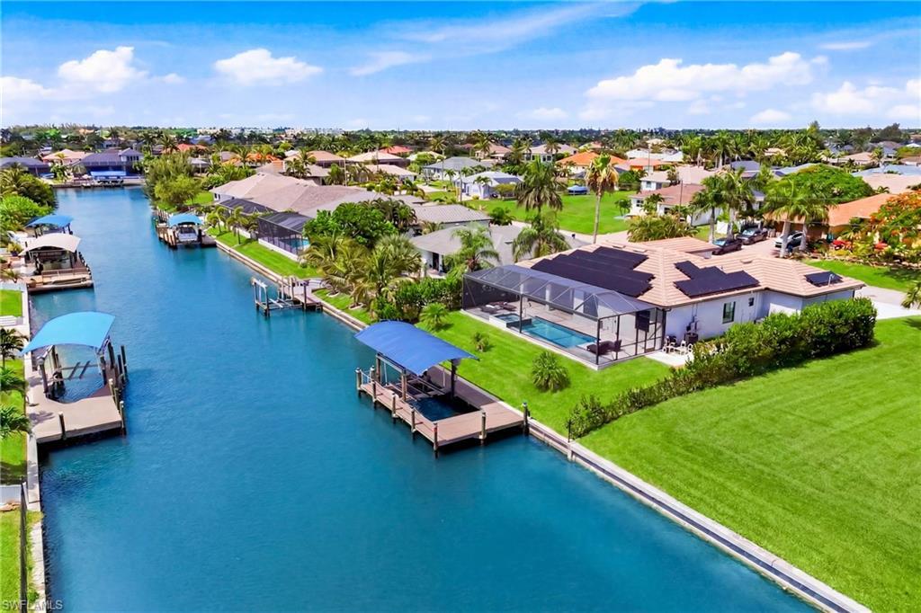Image 1: Waterfront property featuring a private boat dock with canopy, screened-in swimming pool, and solar panel installation