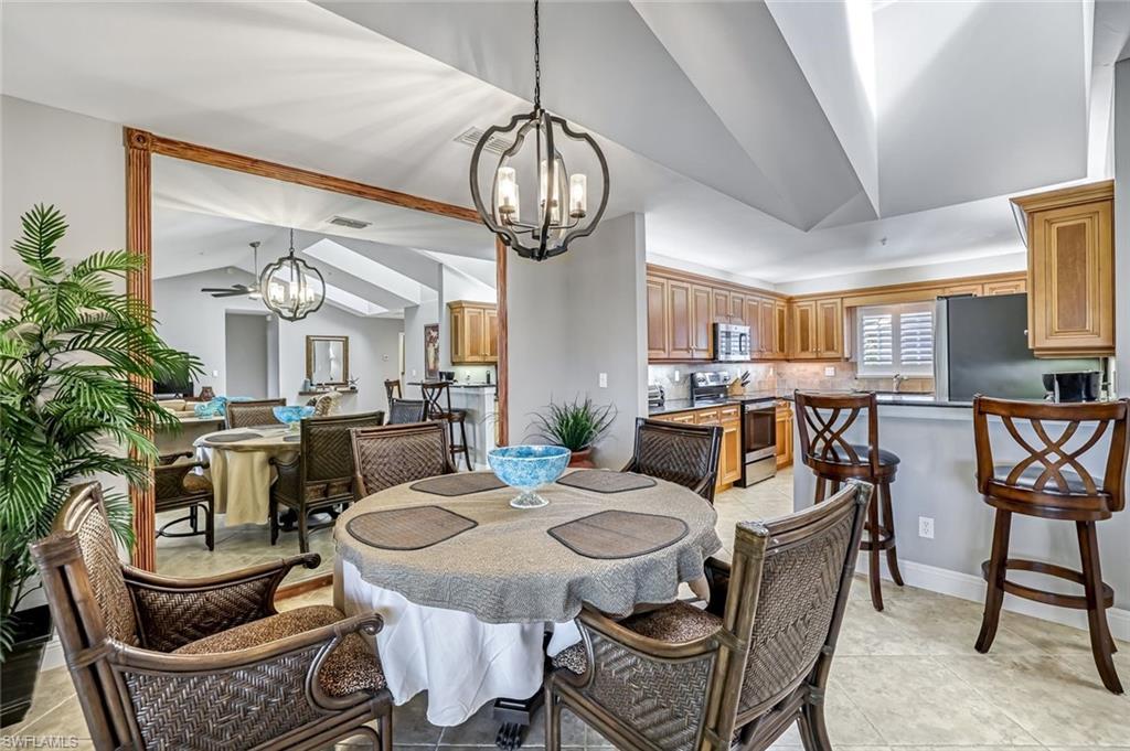 Image 2: Dining area with vaulted ceiling, hanging lights, and light tile patterned flooring