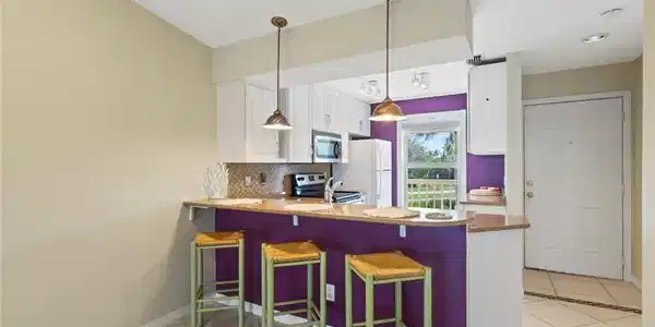 Image 4: Kitchen with a breakfast bar area, light tile patterned floors, a peninsula, white cabinets, and backsplash