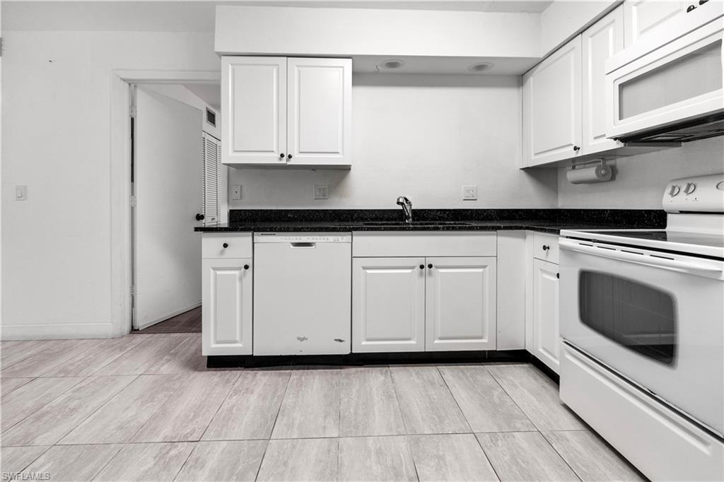 Image 3: Kitchen with white appliances, white cabinets, and dark stone counters