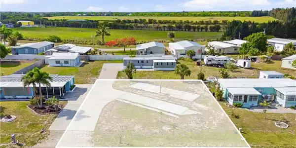 Image 2: Cleared lot featuring a paved driveway and visible utility hookups