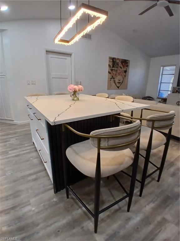 Image 4: Kitchen island featuring a white countertop with dark veining, integrated storage drawers with linear pulls, and a contrasting fluted panel detail