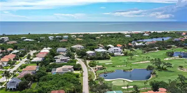 Image 2: Aerial view of residential area with a nearby body of water and a golf club