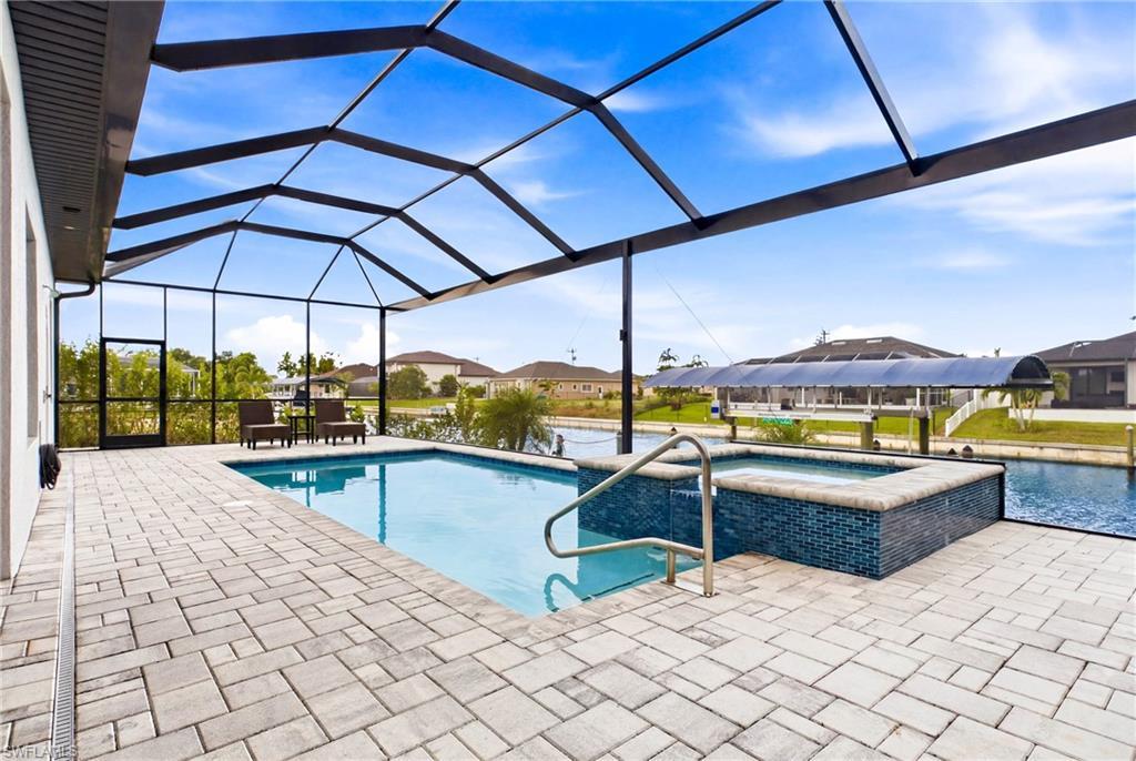 Image 2: Screened lanai featuring a swimming pool and integrated spa with blue mosaic tile