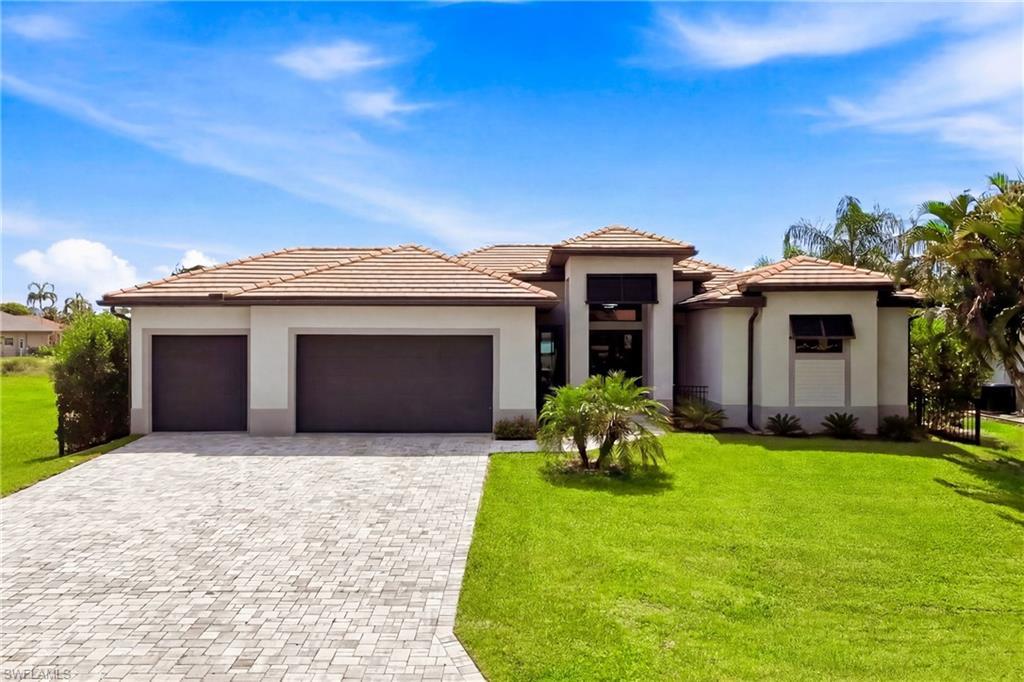 Image 3: Contemporary exterior featuring a paver driveway, two-car garage, tile roofing, and a manicured lawn