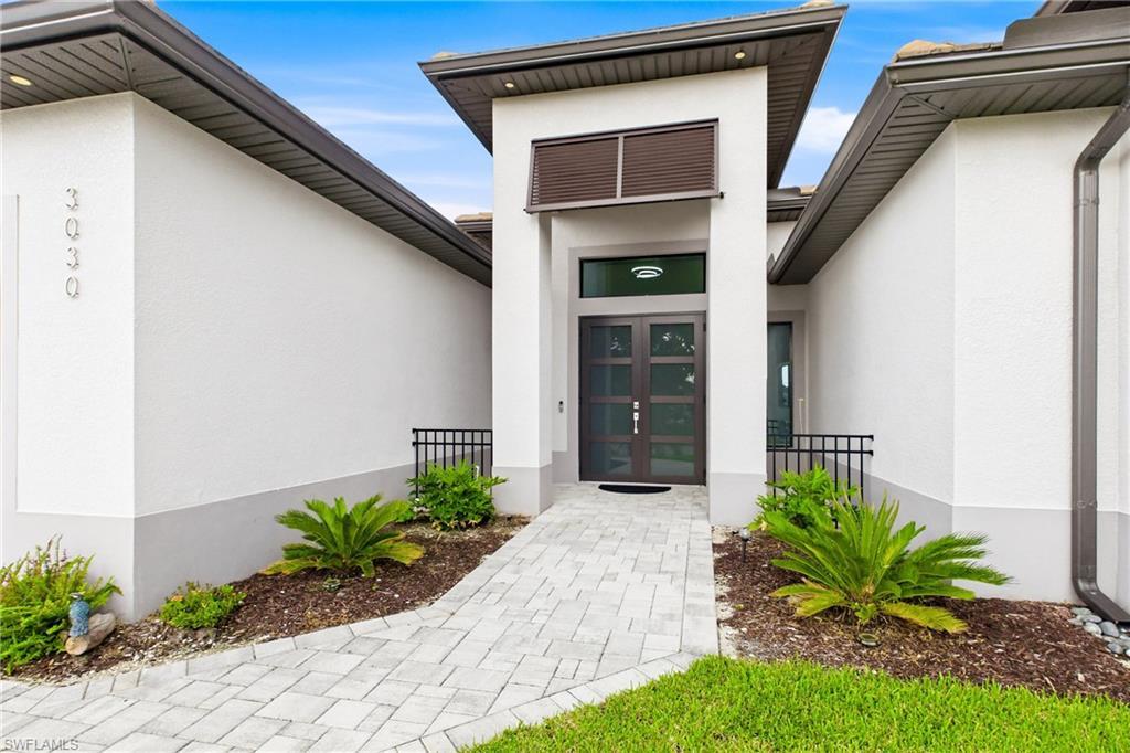 Image 4: Contemporary exterior featuring a stepped entry with a paver walkway, double glass-paneled entry doors, and a decorative slatted transom