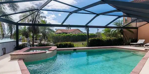 Image 4: View of pool with glass enclosure, an in ground hot tub, a patio area, and a water view