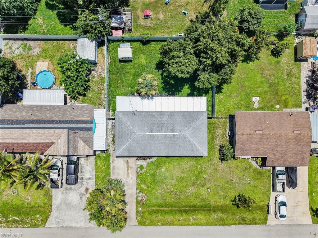 Image 4: Aerial perspective showcasing a residential property with a gray shingle roof, concrete driveway, and established front lawn