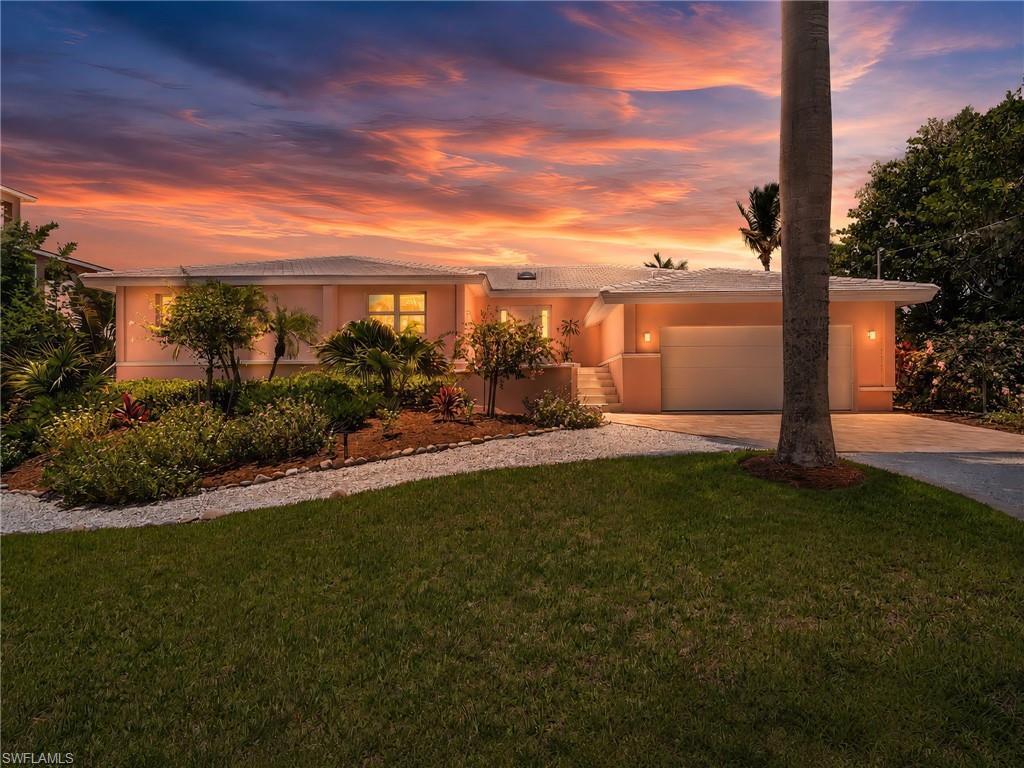 Image 3: Stunning curb appeal with lush tropical landscaping and a welcoming entry.