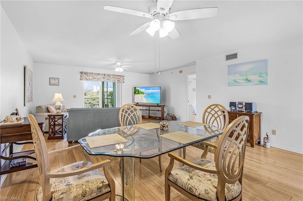 Image 1: Open-concept dining and living area featuring wood-finish flooring, a ceiling fan, and white walls