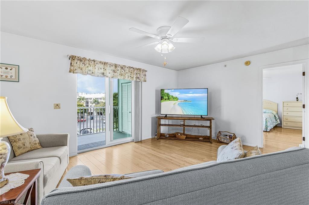 Image 2: Living area featuring wood-finish flooring, white walls, and a white ceiling fan with integrated lighting