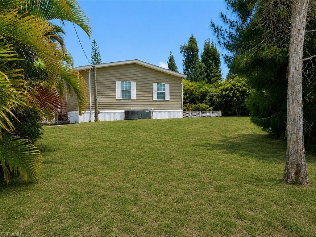 Image 2: Expansive lawn area with mature trees and tropical foliage in the backyard