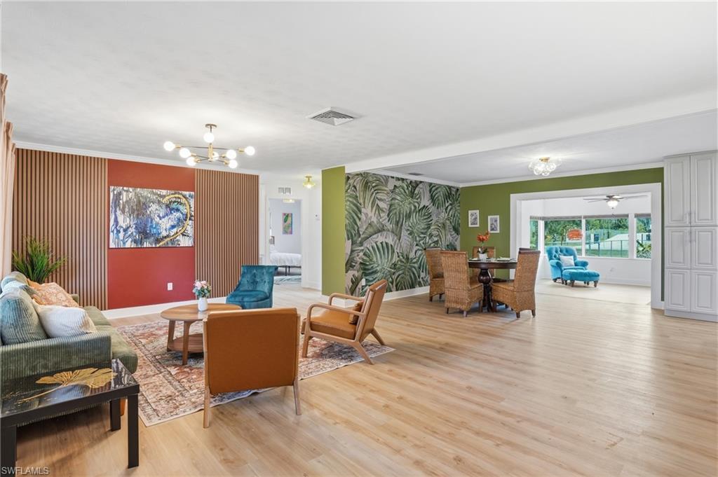 Image 2: Open-concept living area featuring LVP flooring, a contemporary chandelier, and recessed lighting