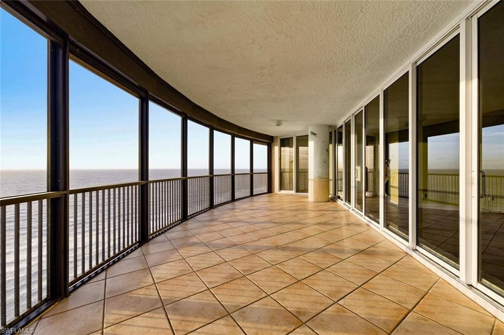 Image 3: Expansive curved balcony featuring tile flooring and a black metal railing