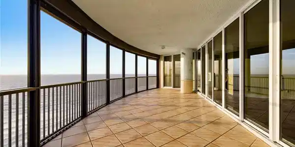 Image 3: Expansive curved balcony featuring tile flooring and a black metal railing