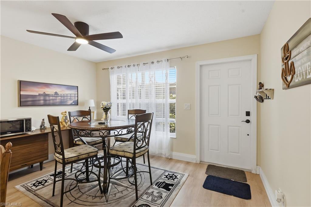Image 2: Dining area featuring wood-finish flooring, a contemporary ceiling fan with integrated lighting, and a white paneled entry door