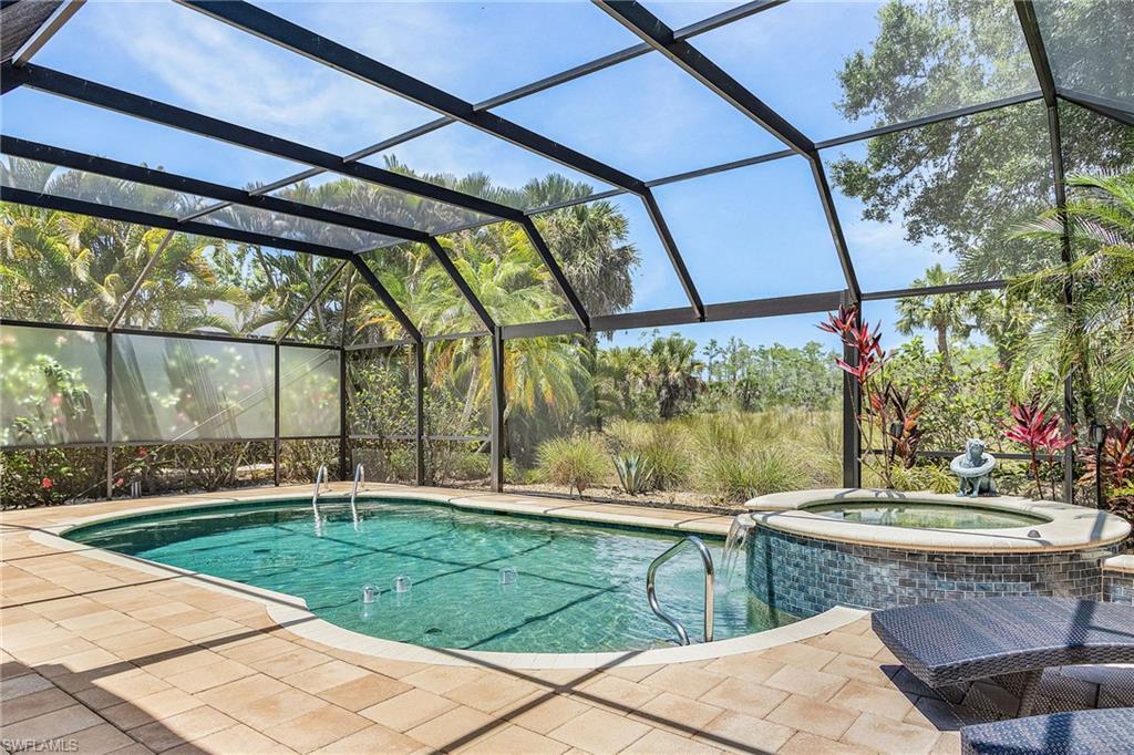 Image 2: Screened lanai featuring an in-ground pool and integrated spa with a waterfall feature