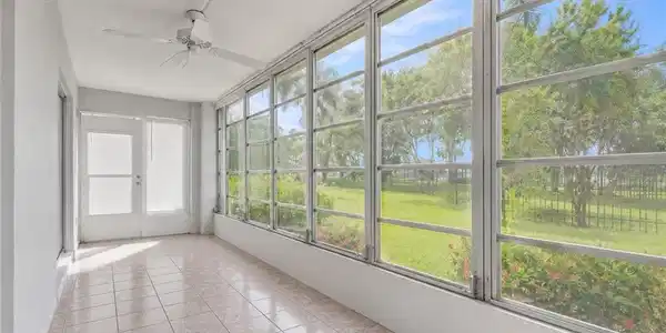 Image 3: Enclosed sunroom featuring a full wall of windows, tile flooring, a ceiling fan, and access to the exterior