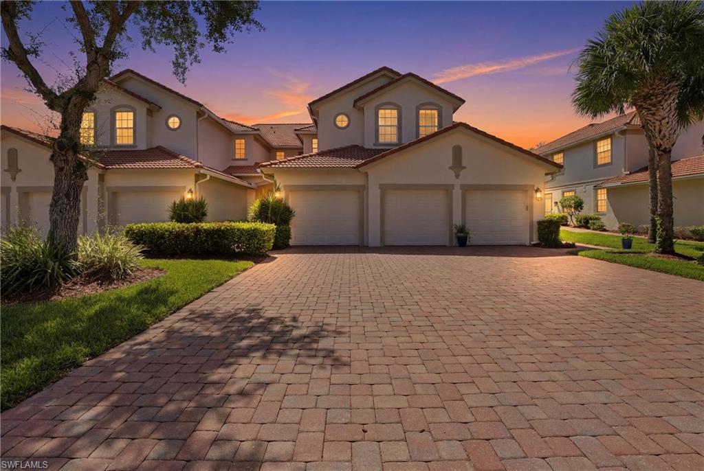 Image 1: Paver driveway leading to a row of residences featuring barrel tile roofs, stucco exteriors, attached garages, and circular accent windows