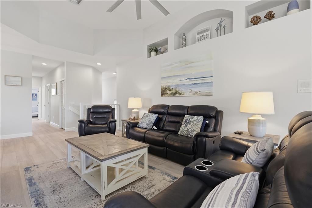 Image 3: Vaulted ceiling living area featuring light wood-finish flooring, recessed lighting, and integrated wall niches
