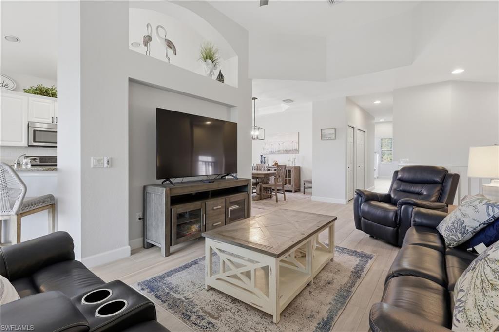 Image 4: Open-concept living area featuring light wood-finish flooring, recessed lighting, and a tray ceiling