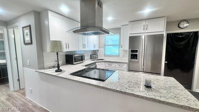 Image 3: Modern kitchen featuring white shaker cabinetry, stainless steel appliances, a built-in cooktop, and speckled light-tone countertops