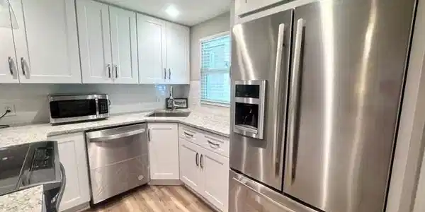 Image 4: Kitchen featuring white shaker cabinetry, stainless steel appliances, speckled countertops, a white subway tile backsplash, and wood-finish flooring