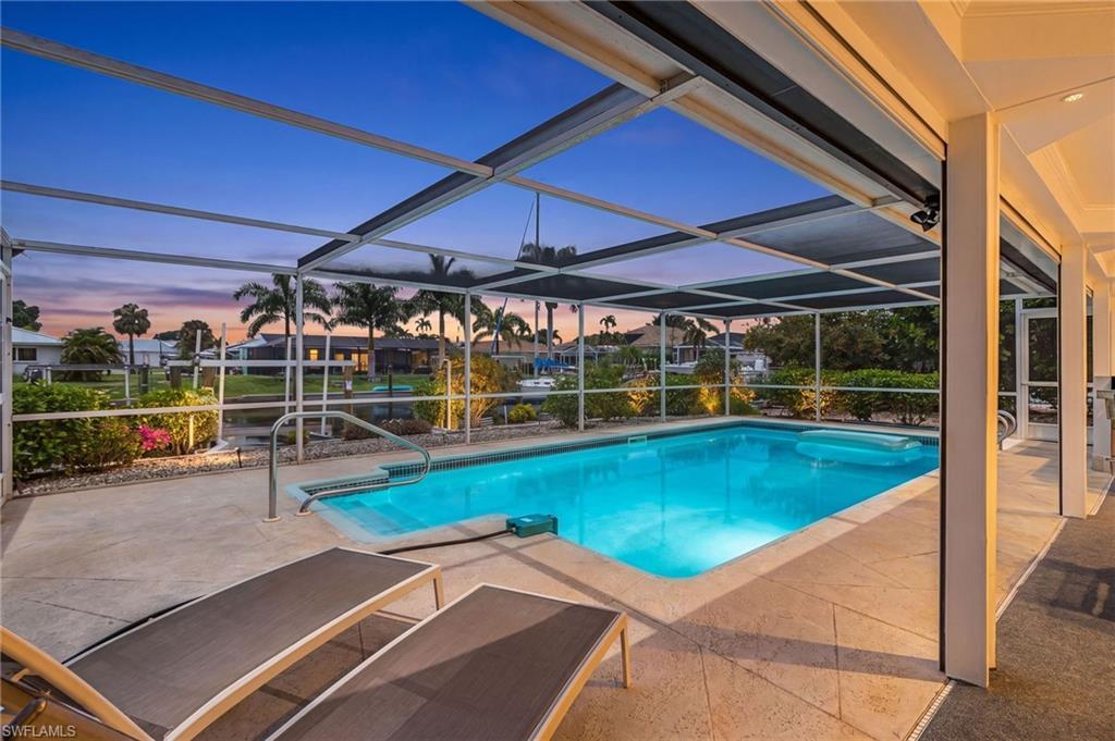 Image 2: Screened swimming pool with a concrete paver deck and direct water access - no light in pool