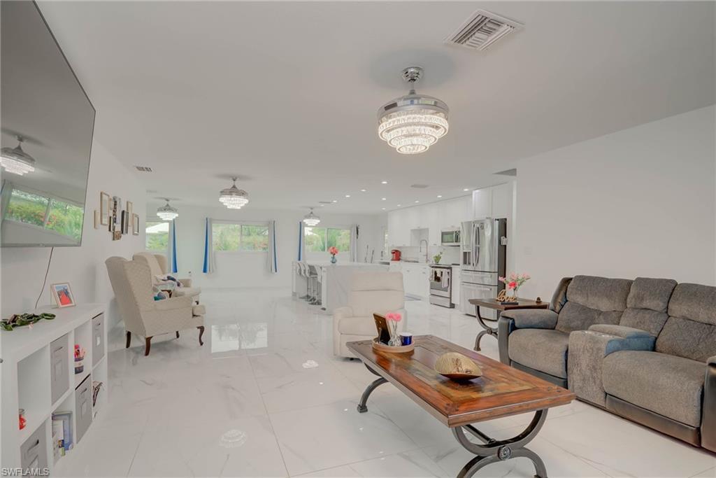Image 2: Open-concept living space featuring high-gloss tile flooring, recessed lighting, and multiple crystal-tiered ceiling fixtures